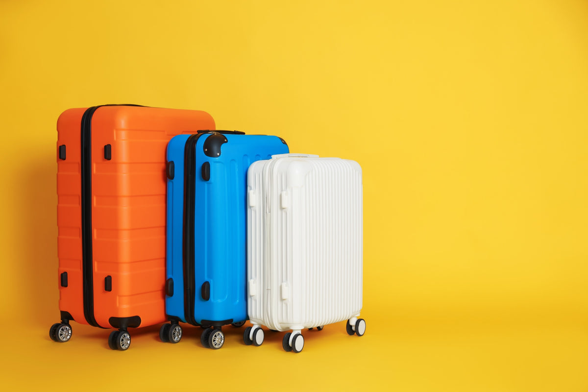 Three colourful suitcases on a yellow background