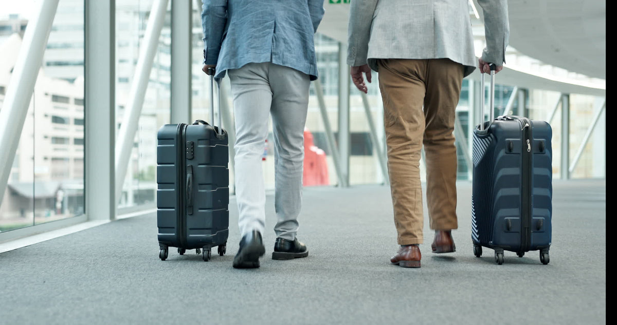 Two travellers walking through an airport with luggage