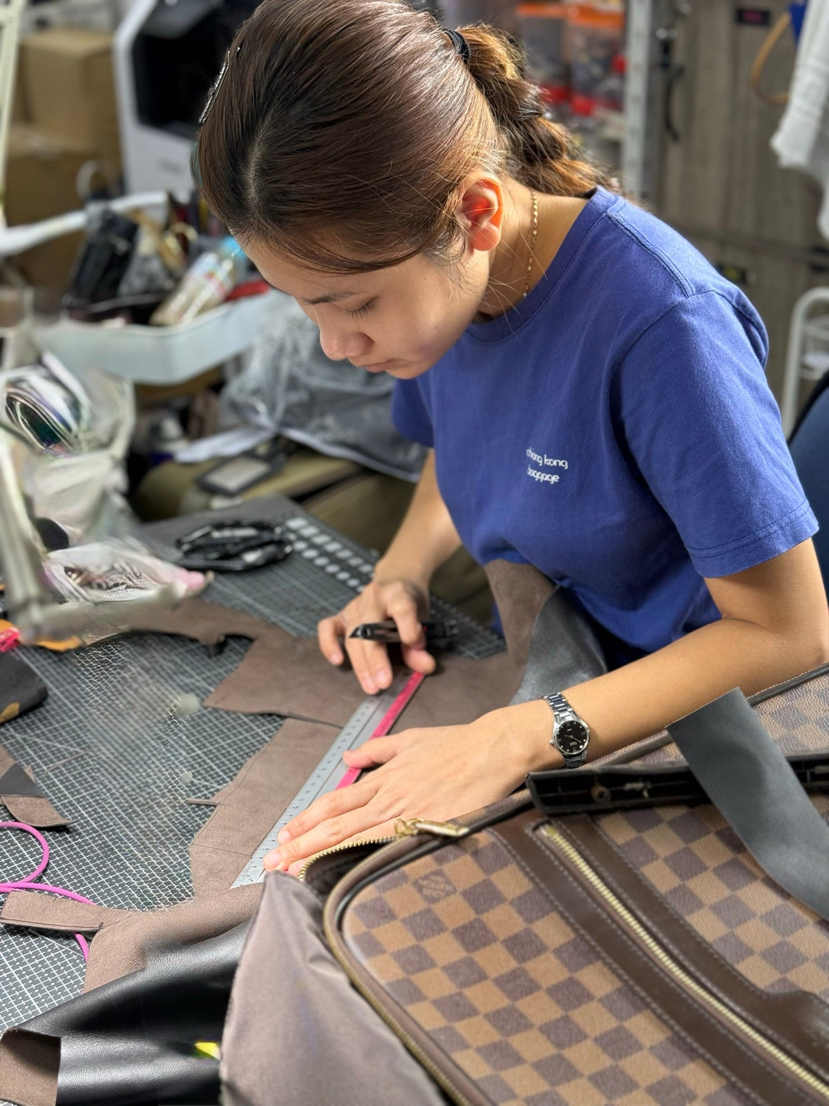 A Chiang Kong craftsperson repairing a bag at the workshop bench