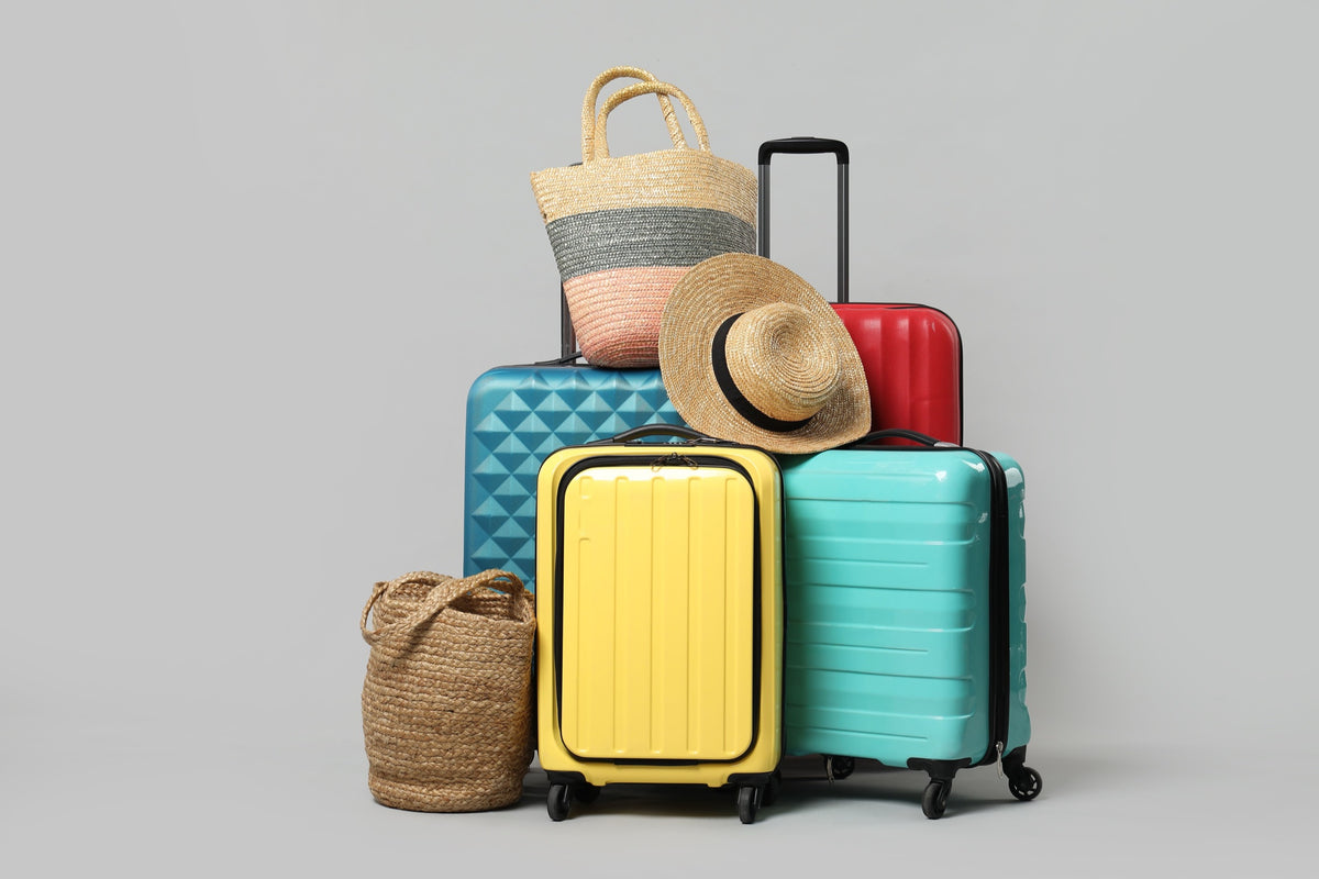 A pile of colourful suitcases, beach bags and a straw hat
