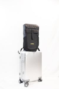 Lumière Reflect Pro backpack sitting on top of an aluminium cabin suitcase