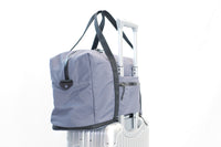 Lumière Utility travel duffel mounted on a suitcase trolley handle via the trolley sleeve